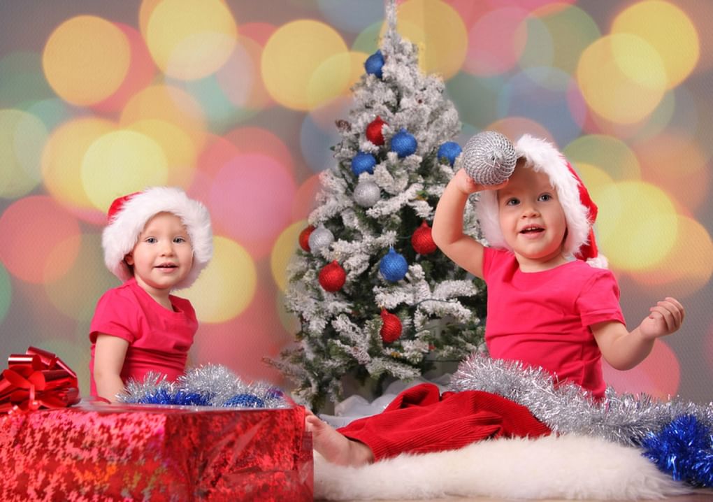 Малыши в новогодних колпаках около елки. Фотография: Т. Гладских / фотобанк «Лори»