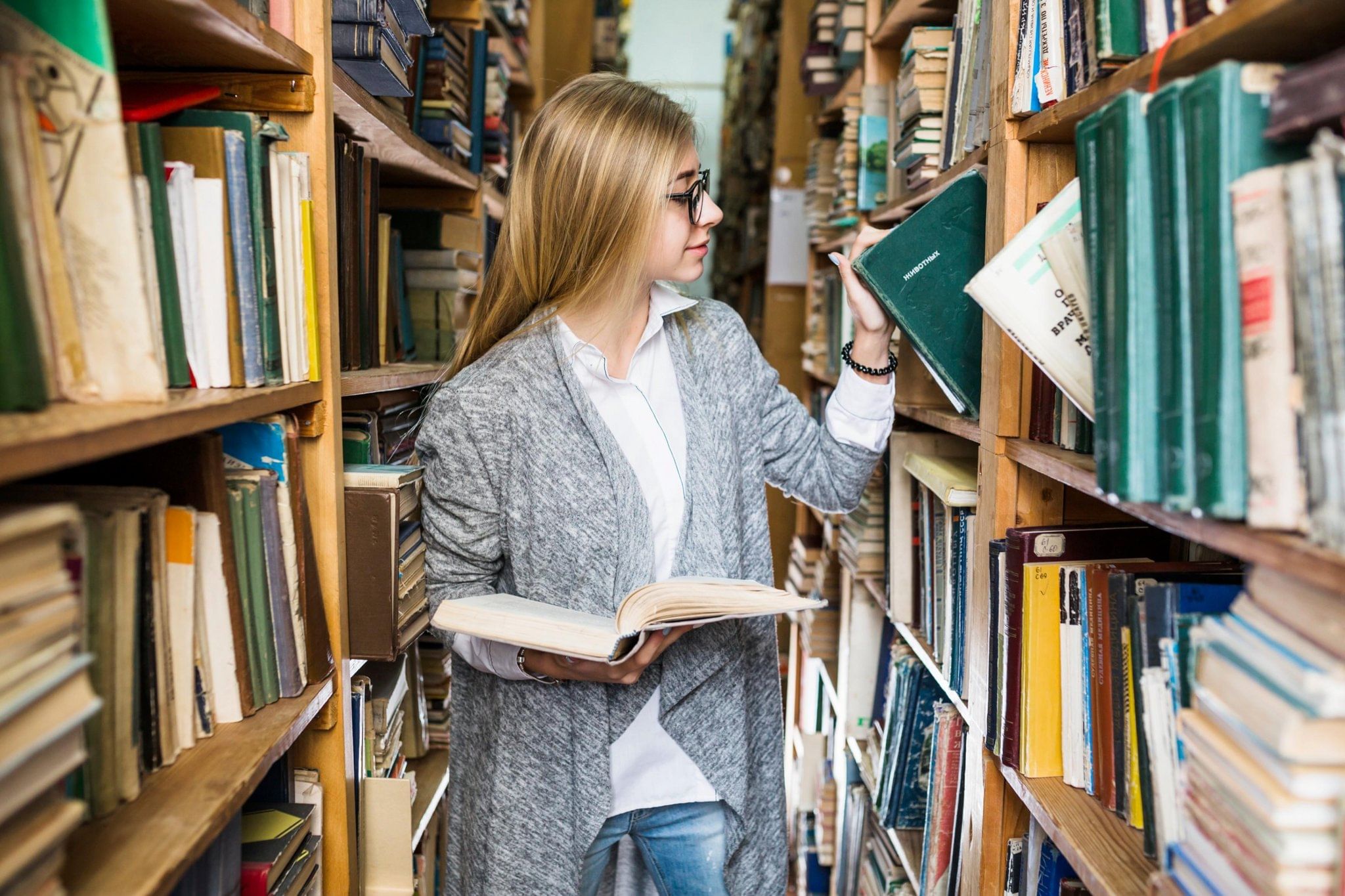Человек берет книгу с полки. Женщина берет книгу с полки. Девушка берет книгу с полки.