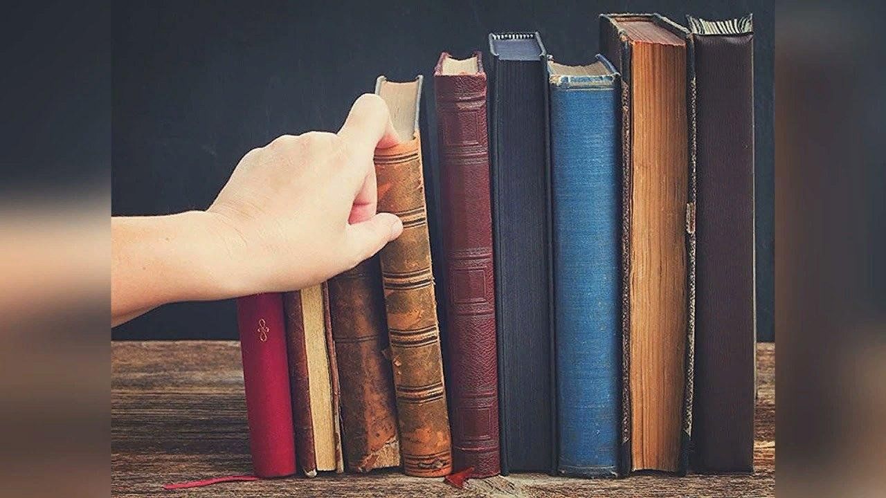 Человек достает книгу с полки