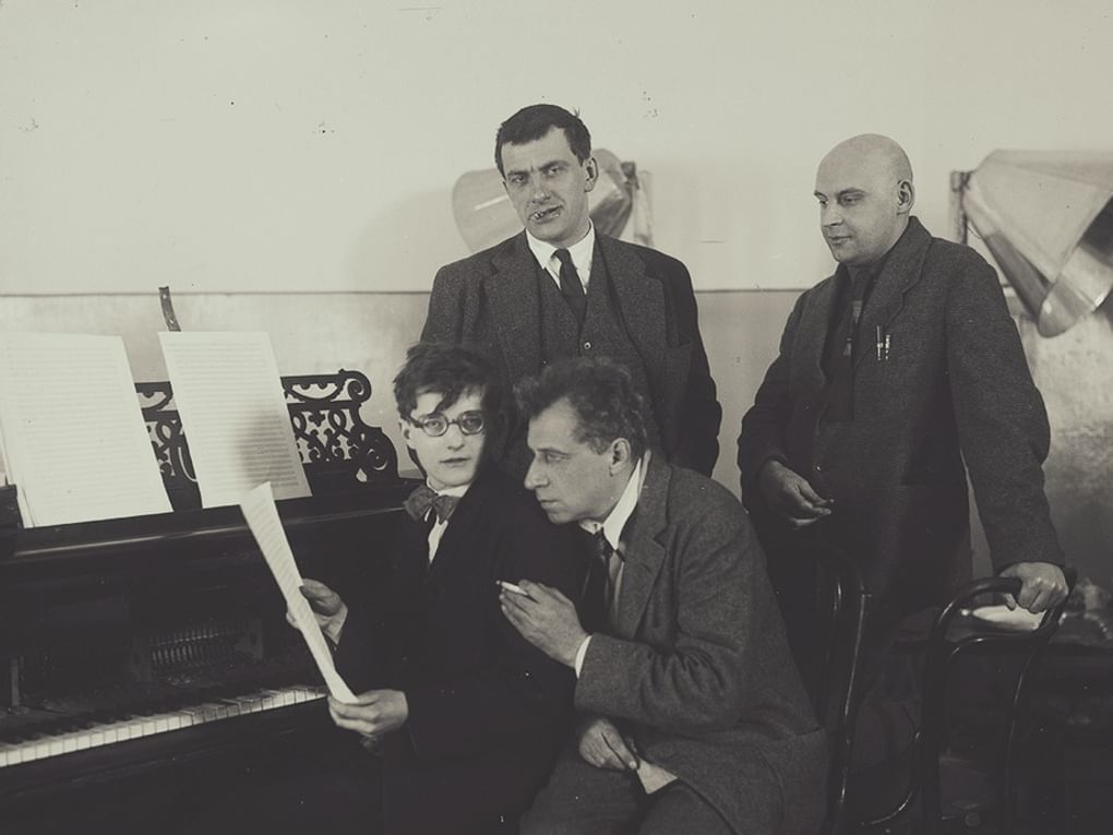 Слева направо: поэт Владимир Маяковский и фотограф Александр Родченко (стоят), композитор Дмитрий Шостакович и режиссер Всеволод Мейерхольд (сидят) у рояля. 1926. Фотография: onedio.ru