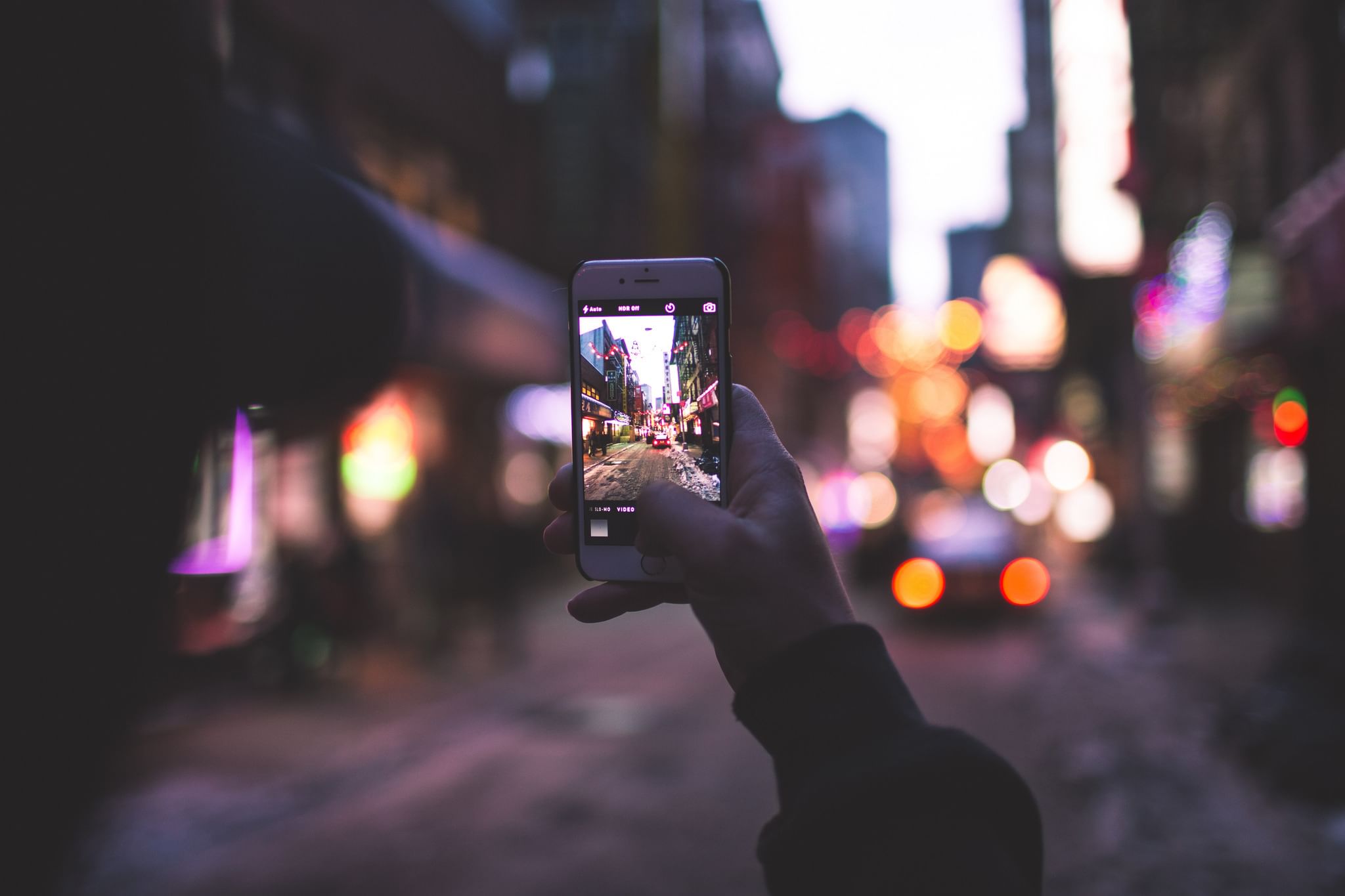 Размытая реальность. Смартфон в руках на улице. Телефон в руке. Ночная съемка на телефон. Фотоаппарат и городские улицы.