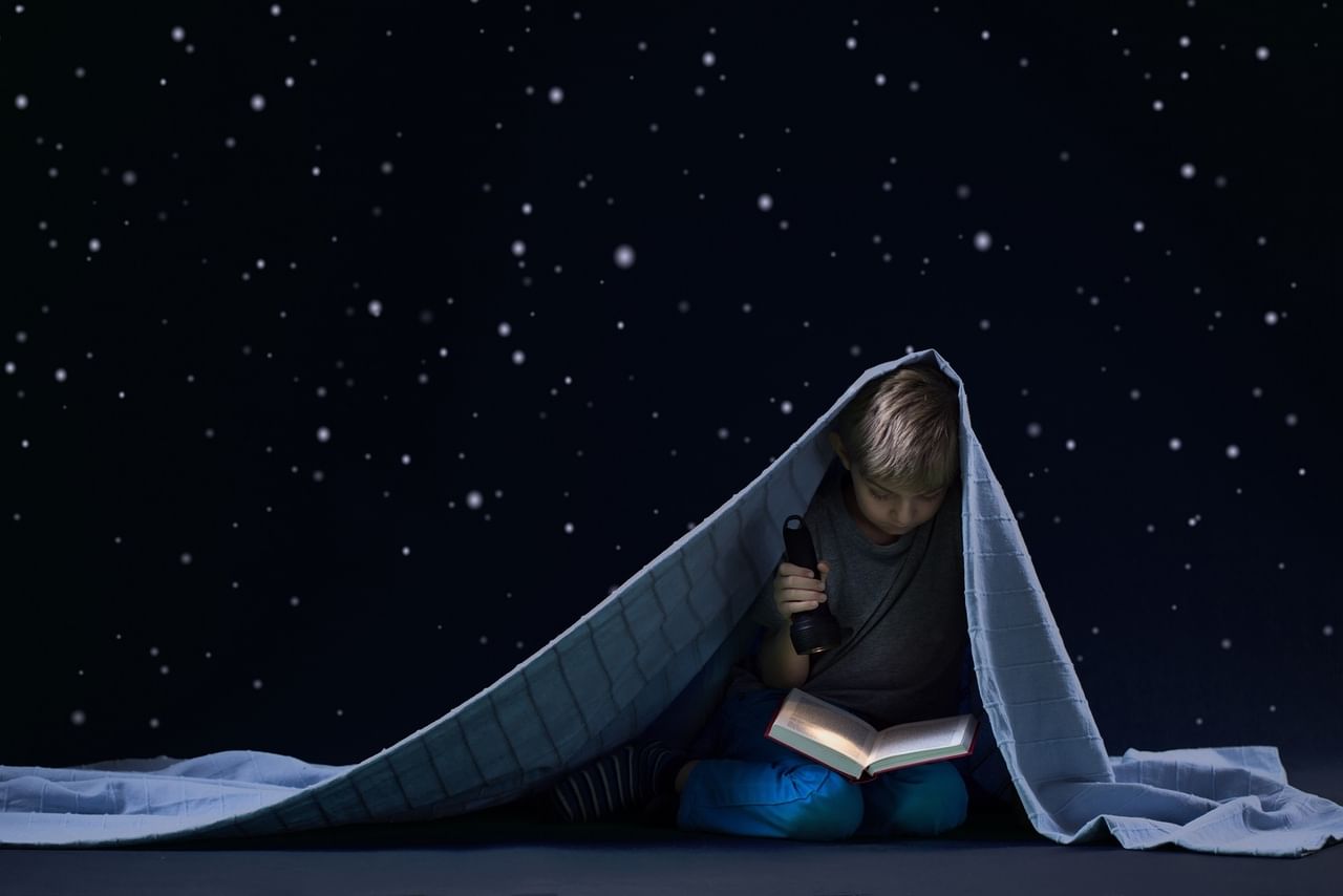 Звезда читает сказку. Чтение под одеялом. Чтение под одеялом с фонариком. Книга ночи. Ребенок под одеялом ночью.